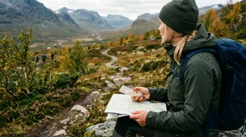 Kvinnlig vandrare navigerar med karta och kompass på en fjällstig i höstfärger